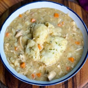 Bowl of chicken and dumplings – A close-up of a white bowl filled with creamy chicken and dumplings, featuring tender shredded chicken, chunks of carrots, and fluffy biscuit dumplings on top.