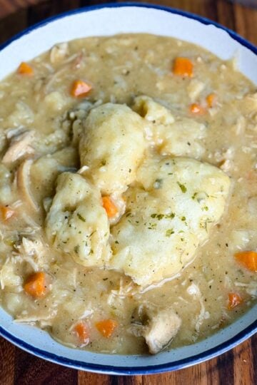 Bowl of chicken and dumplings – A close-up of a white bowl filled with creamy chicken and dumplings, featuring tender shredded chicken, chunks of carrots, and fluffy biscuit dumplings on top.