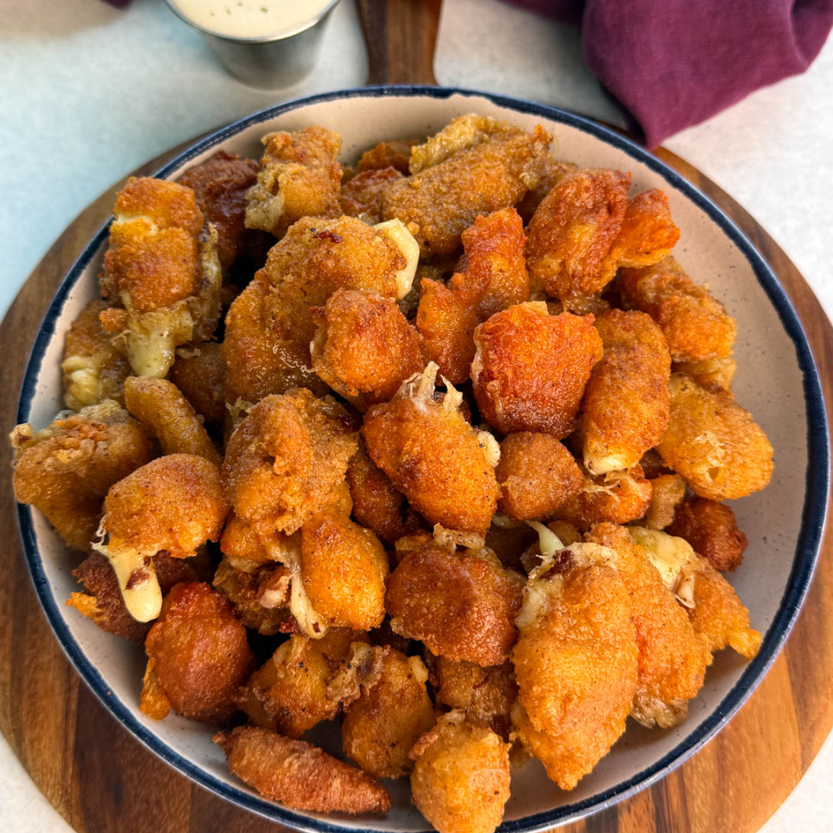 Overhead view of a large bowl filled with crispy fried cheese curds, showing crunchy coating and bits of melty cheese peeking through.