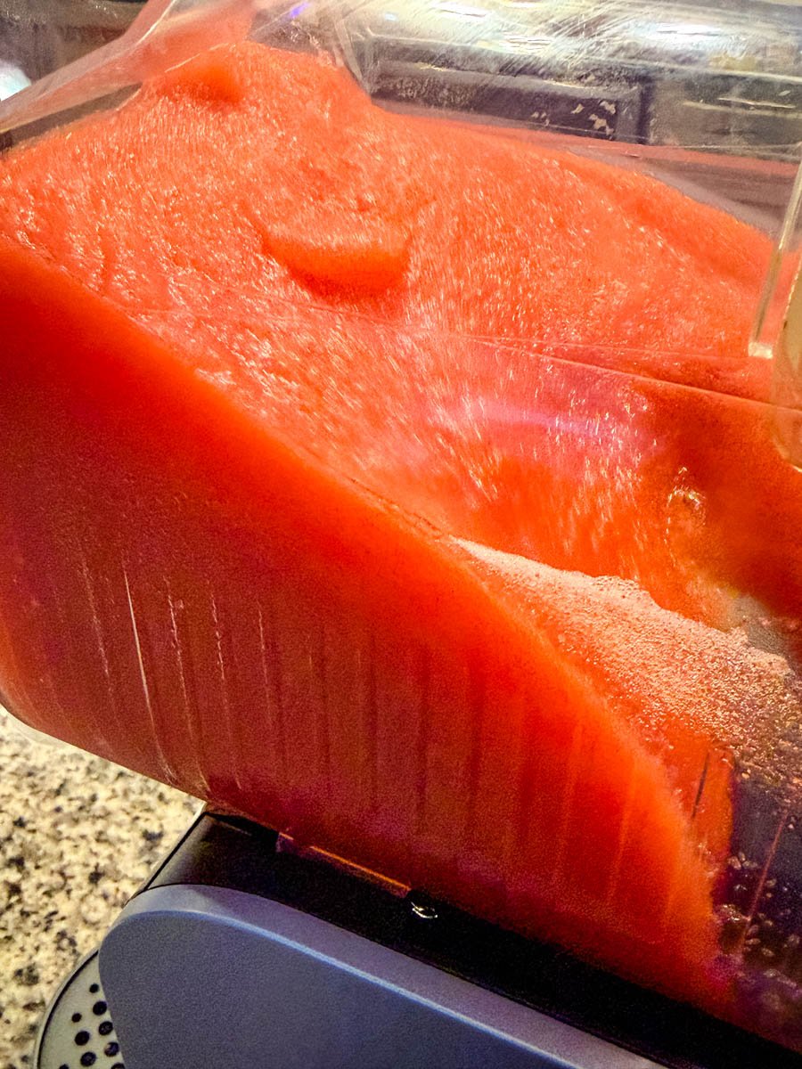 Thick, bright red Hennessy slush mixture freezing inside the Ninja Slushi machine, showing the icy texture up close.