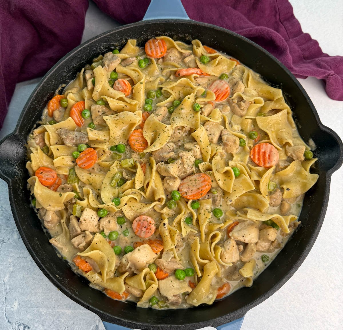 Overhead view of the finished one-pot chicken pot pie casserole with noodles, carrots, peas, and chicken, showing the creamy sauce texture and hearty mix of ingredients.