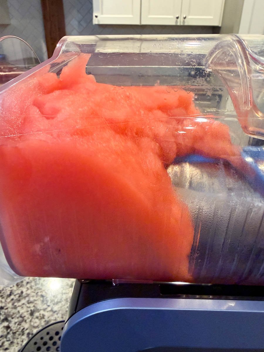 Frozen slushi mixture inside the Ninja Slushi machine showing a smooth, fluffy red texture.