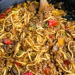 Close-up shot showing saucy Mongolian ground beef noodles with red peppers, mushrooms, and bits of green vegetables, highlighting the glossy, caramelized texture of the sauce.