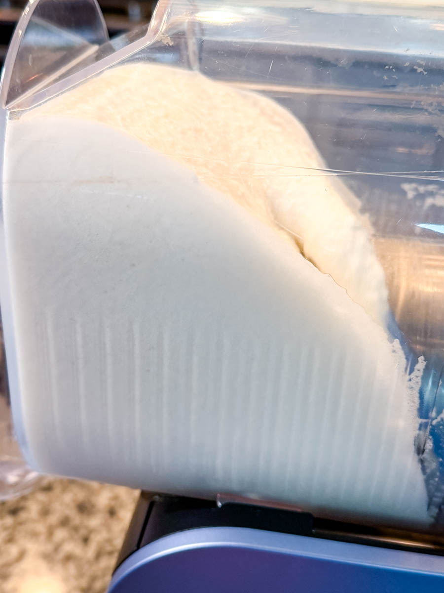 A close-up of the milkshake mixture freezing inside the Ninja Slushi chamber, showing a smooth, thick, icy texture forming along the sides.