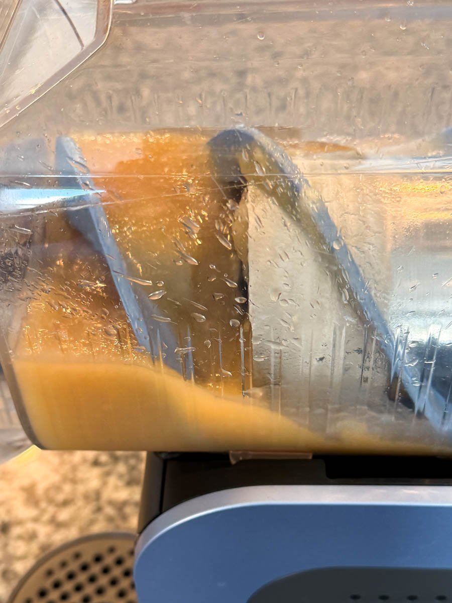 A close-up of the Ninja Slushi machine’s freezing chamber showing the golden Butter Beer mixture starting to freeze and form icy layers along the auger.