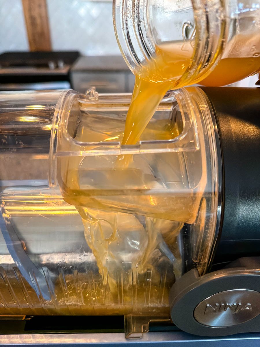 A clear view of the Butter Beer liquid being poured from a mason jar into the top opening of the Ninja Slushi machine.