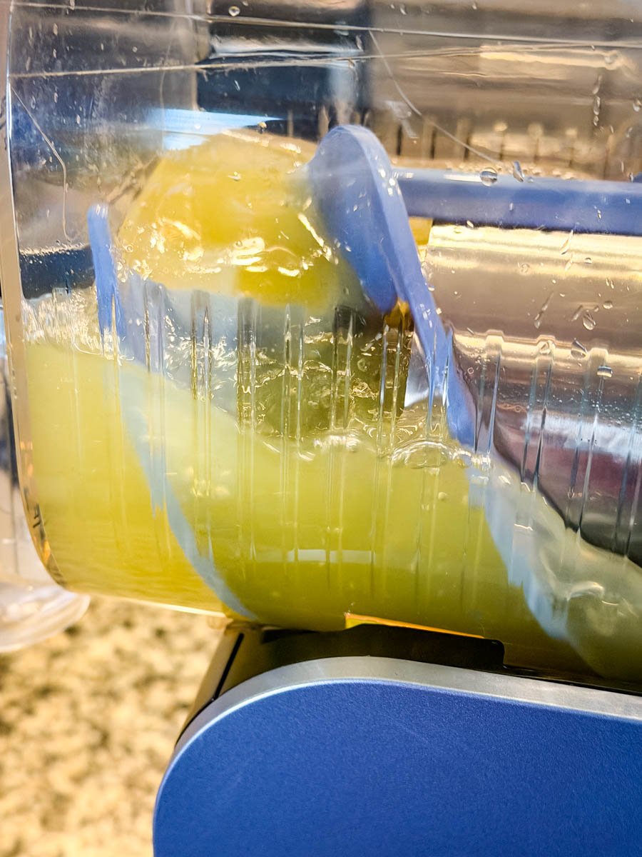Inside the Ninja slushi machine showing the lemon drop mixture partially frozen, with the rotating paddle blending the lemon drop slush ingredients.