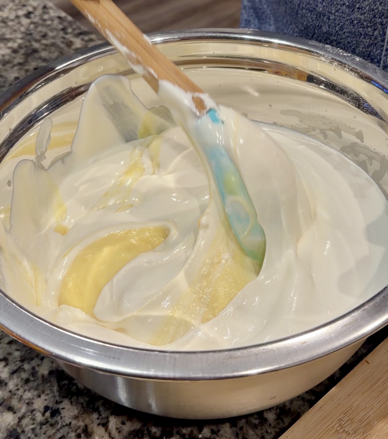 Banana pudding base with sweetened condensed milk and Cool Whip being gently folded together in a large mixing bowl.