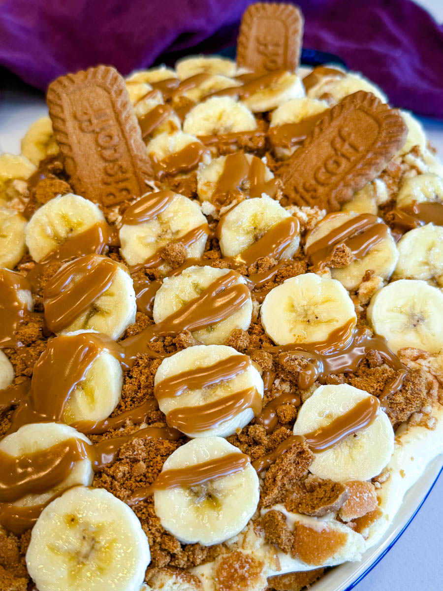Crushed Biscoff cookies and vanilla wafers layered over banana pudding base in a baking dish.