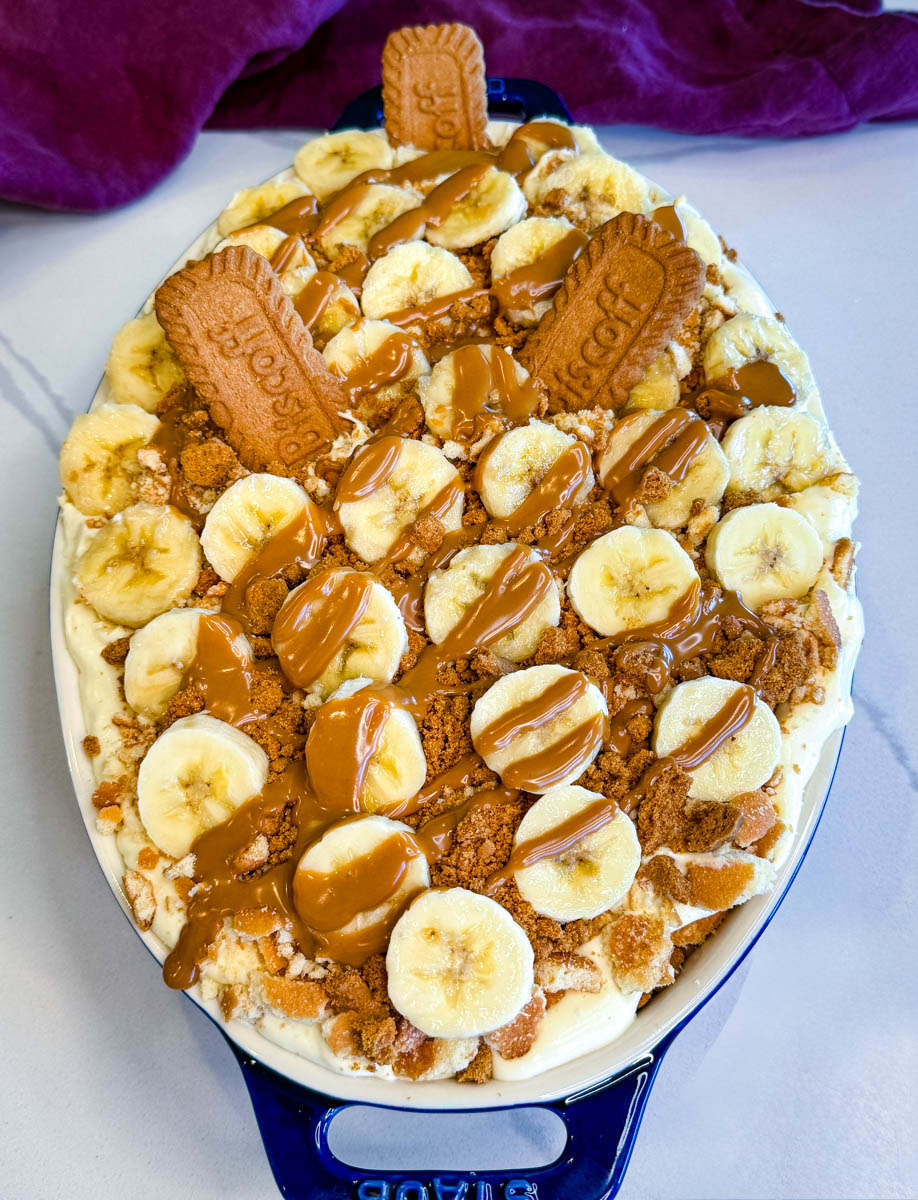 Finished banana pudding topped with banana slices, crushed cookies, whole Biscoff biscuits, and cookie butter drizzle.