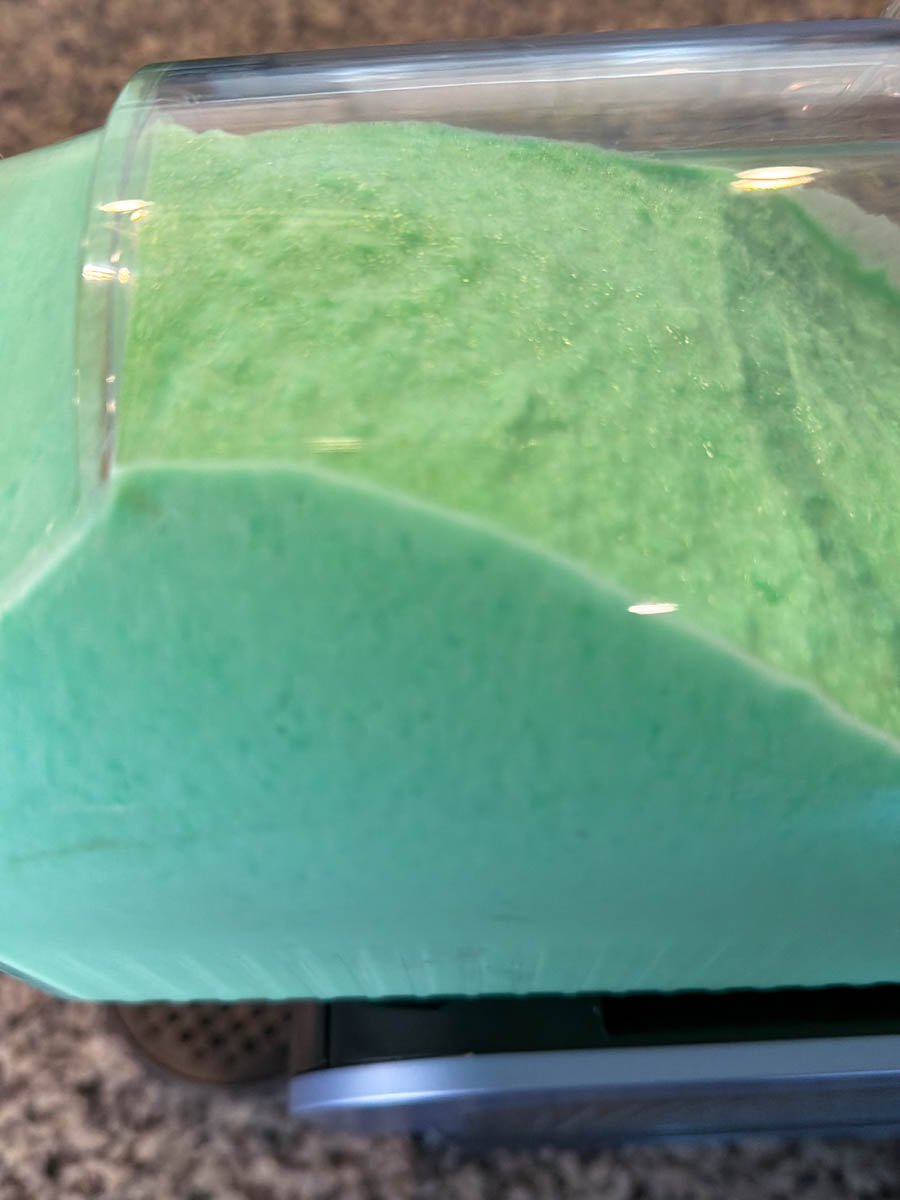 Close view of green shamrock shake mixture churning inside a Ninja Slushi machine.