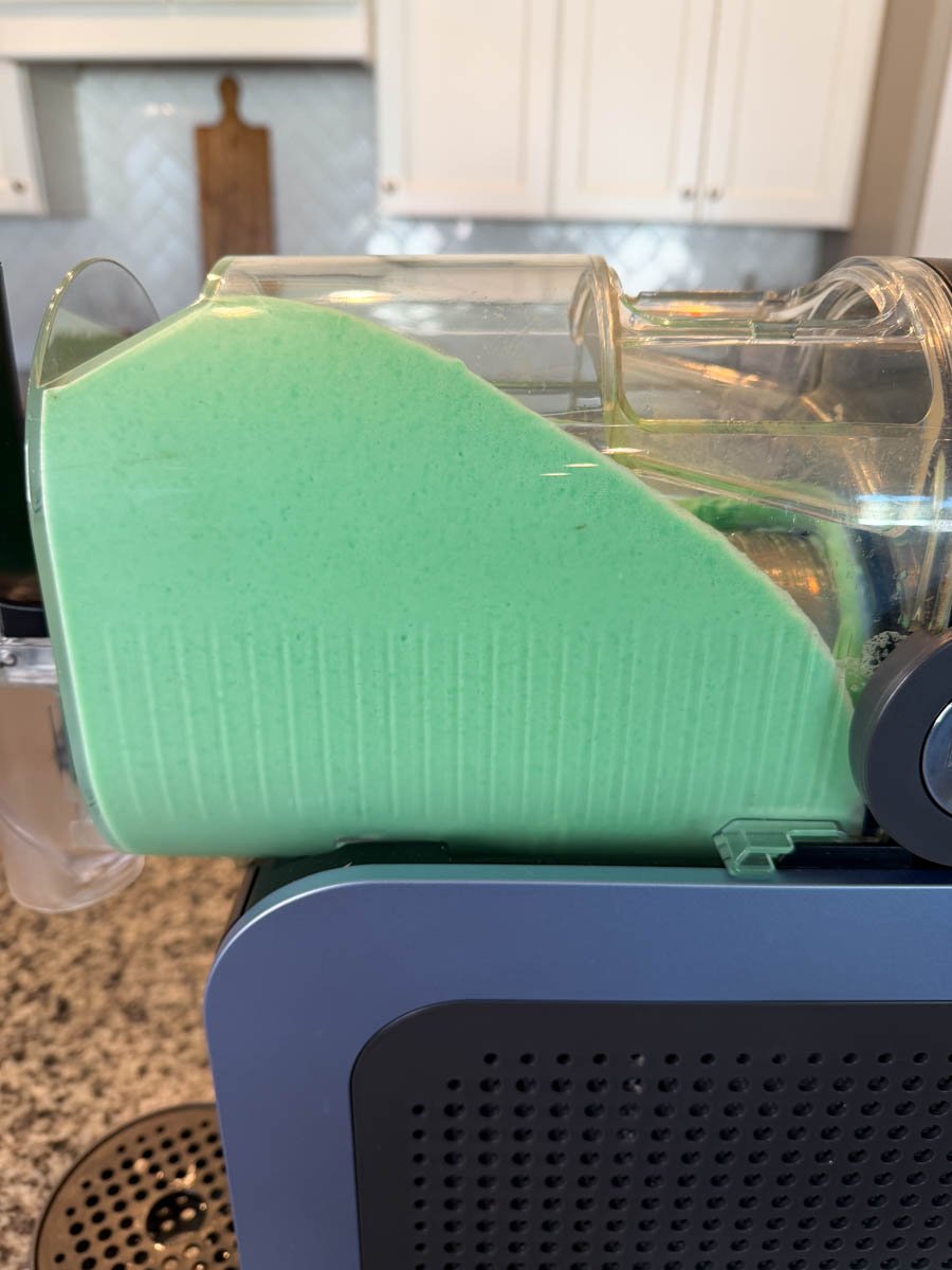 Side view of mint shake mixture freezing in the Ninja Slushi machine chamber.