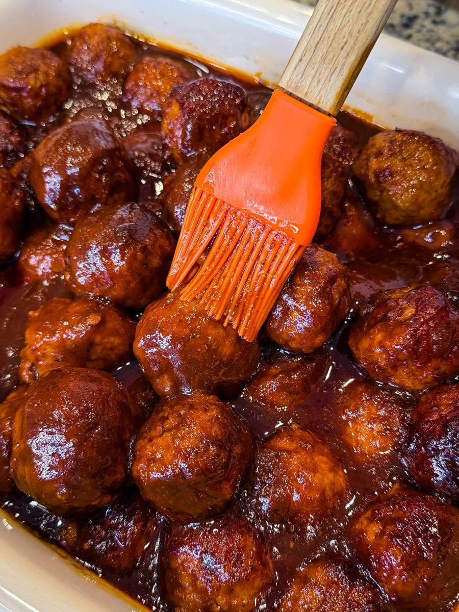 Brush glazing BBQ sauce over meatballs for extra flavor and shine
