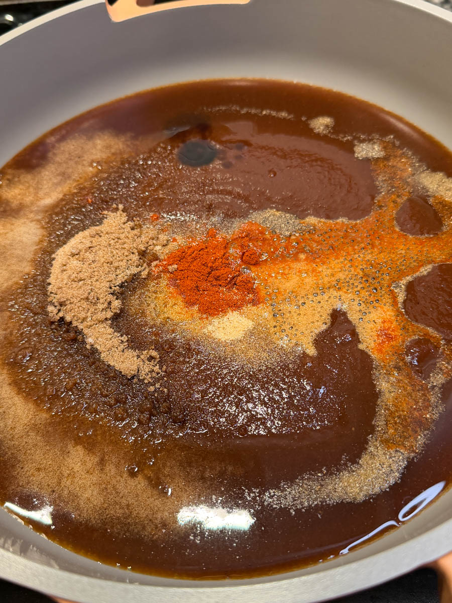 BBQ sauce mixture with brown sugar, spices, and seasonings being combined in a pan