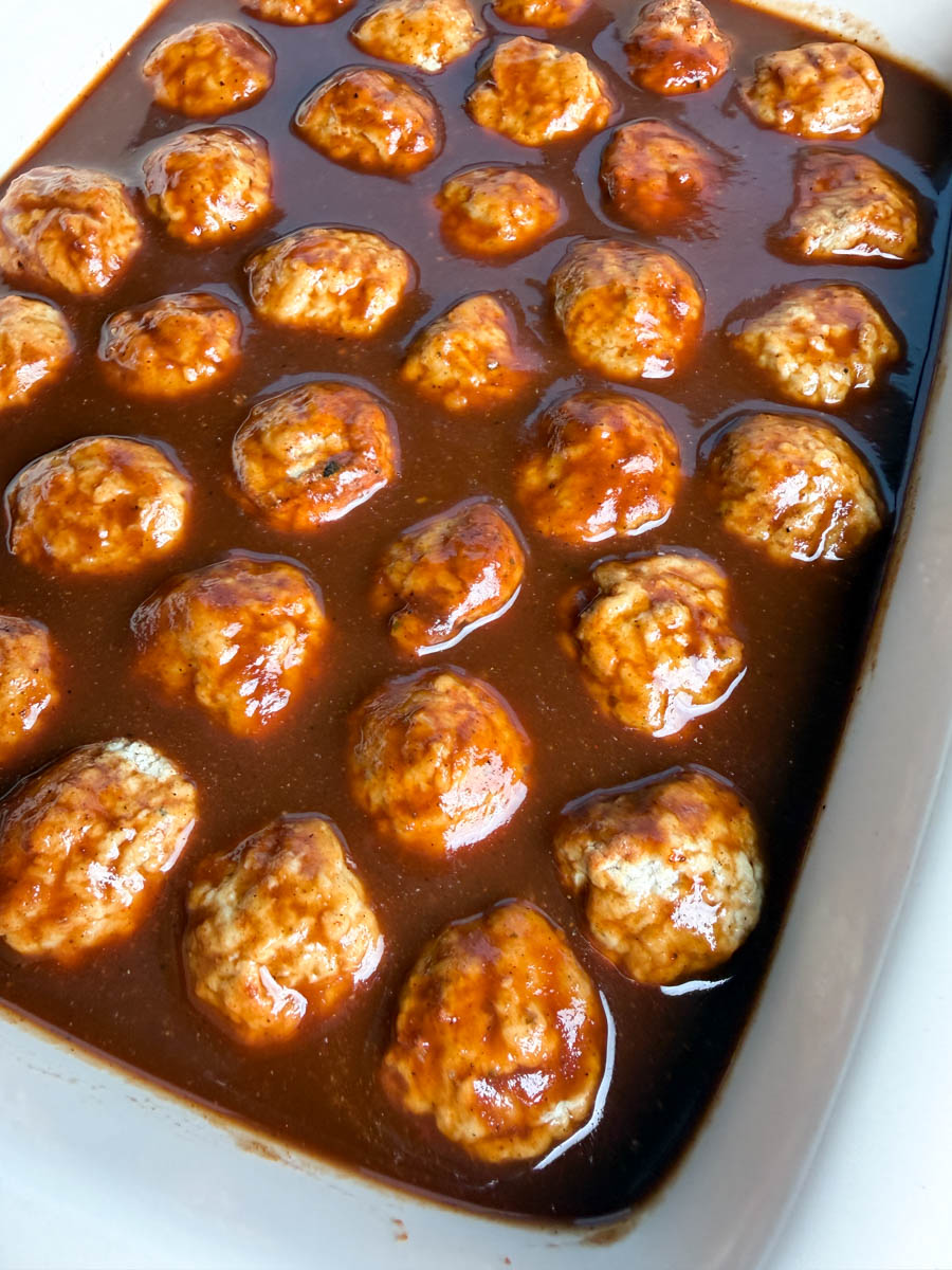 Close-up of meatballs soaking in sweet and savory BBQ sauce before cooking