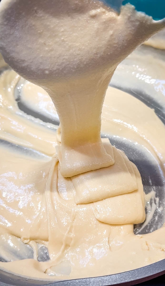 Thick marshmallow and protein powder mixture being stirred until smooth and stretchy.