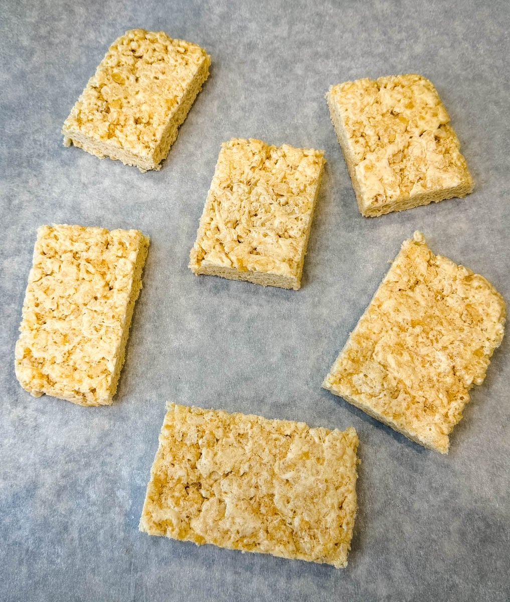 Protein Rice Krispie treats cut into squares without toppings arranged on parchment paper.