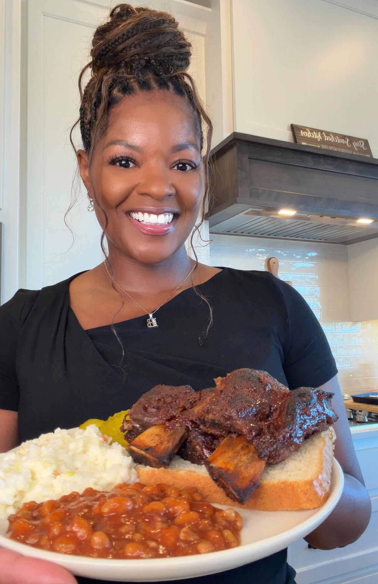 person holding plate of beef ribs, coleslaw, baked beans, and white bread