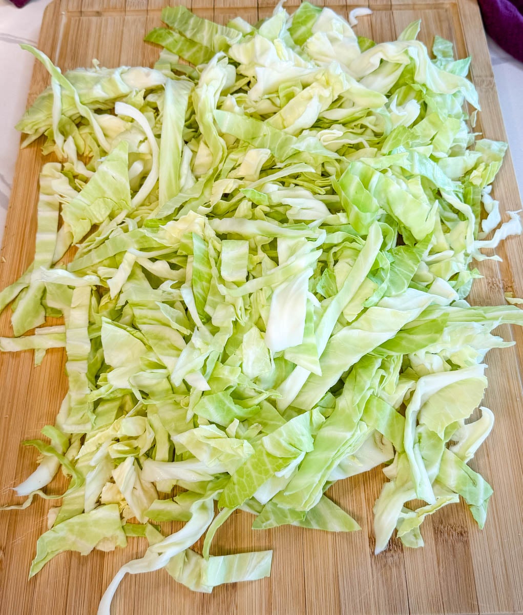 Fresh chopped green cabbage spread on a cutting board, ready for Jamaican steamed cabbage.