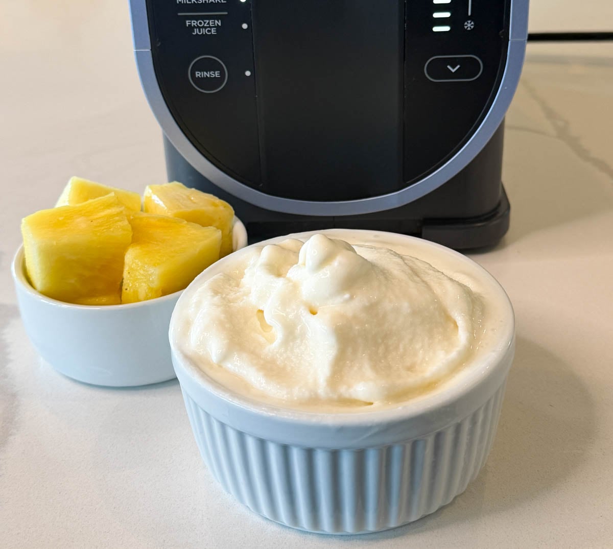 Creamy pineapple Dole Whip made in the Ninja Slushi machine served with fresh pineapple pieces