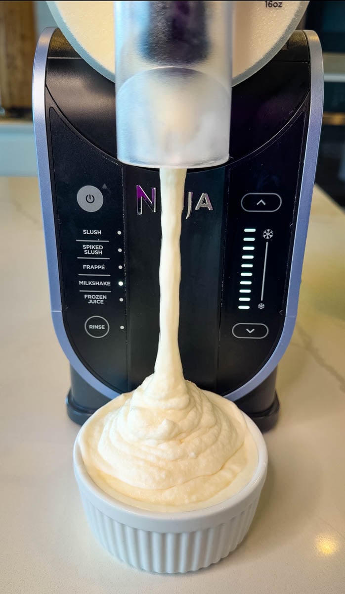 Ninja Slushi pineapple Dole Whip dispensing into a ramekin with thick, creamy soft serve texture