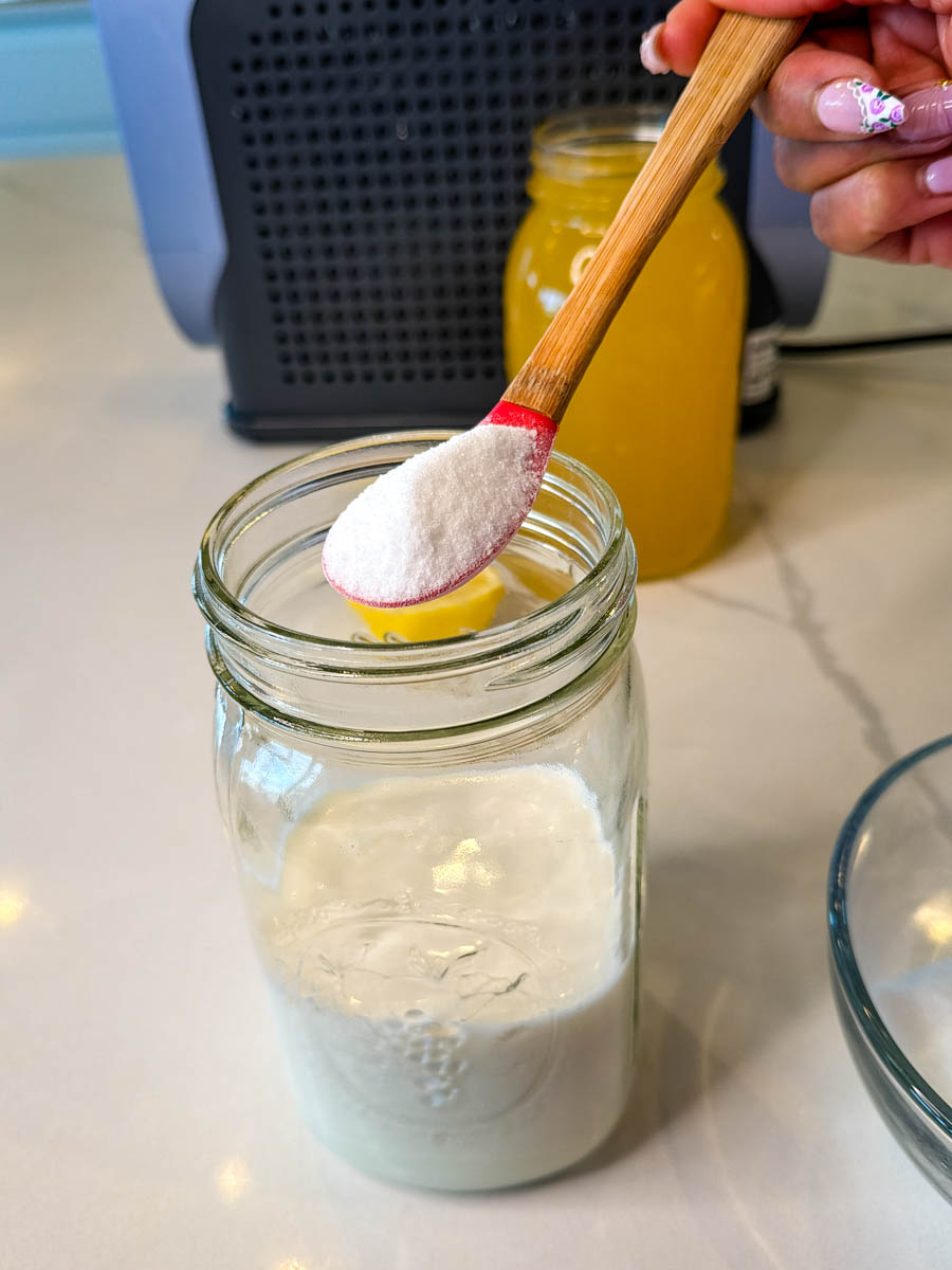 Adding sugar to milk in a mason jar to prepare the base for Ninja Slushi Dole Whip recipe