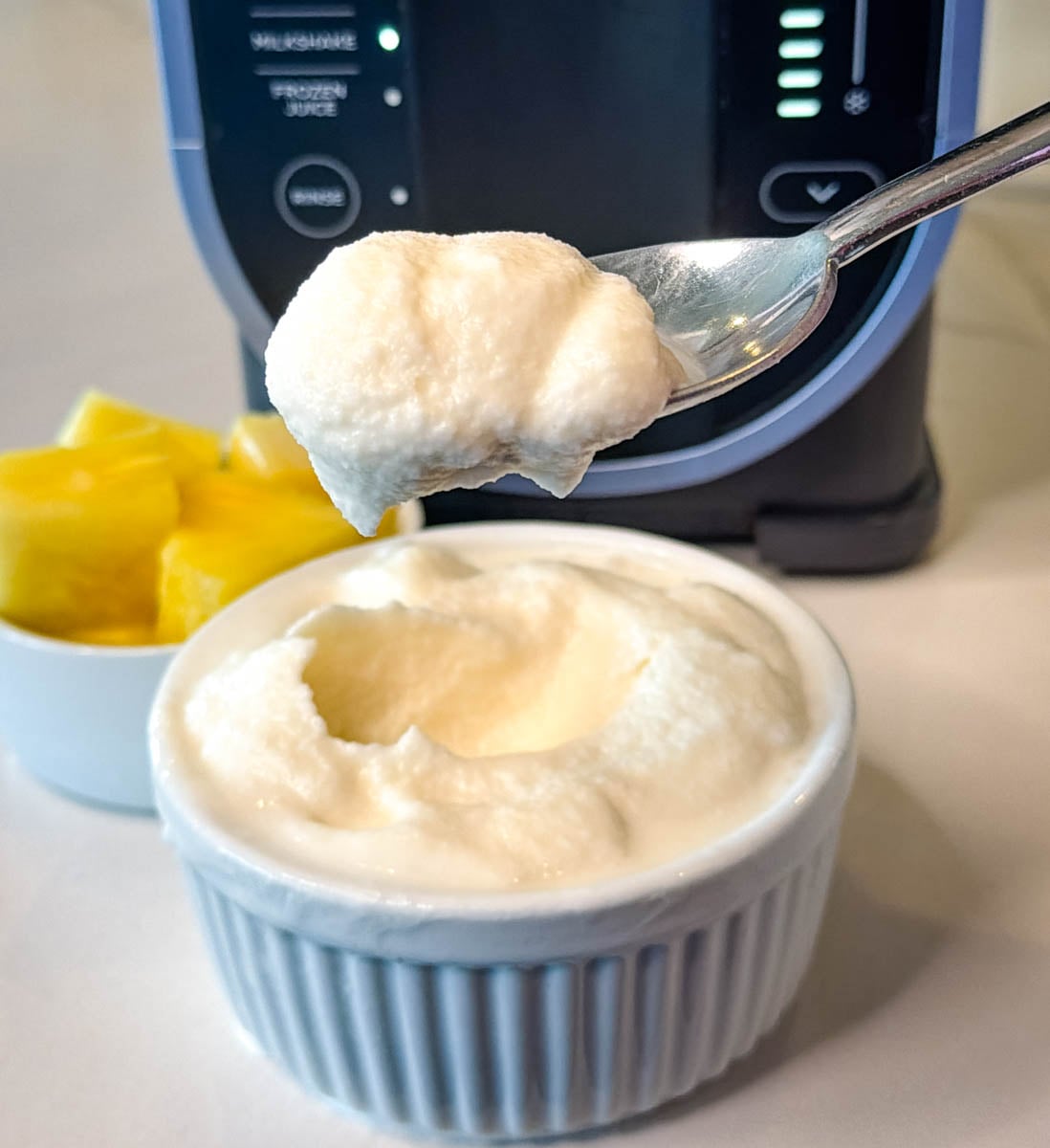 Spoonful of thick, soft-serve style Ninja Slushi Dole Whip with pineapple chunks on the side