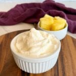 Creamy Ninja Slushi pineapple Dole Whip in a ramekin with fresh pineapple chunks on a wooden board