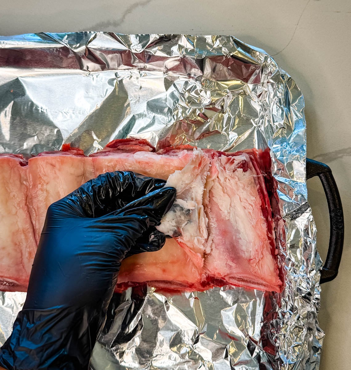 Close-up of peeling off the membrane from the back of beef ribs before seasoning