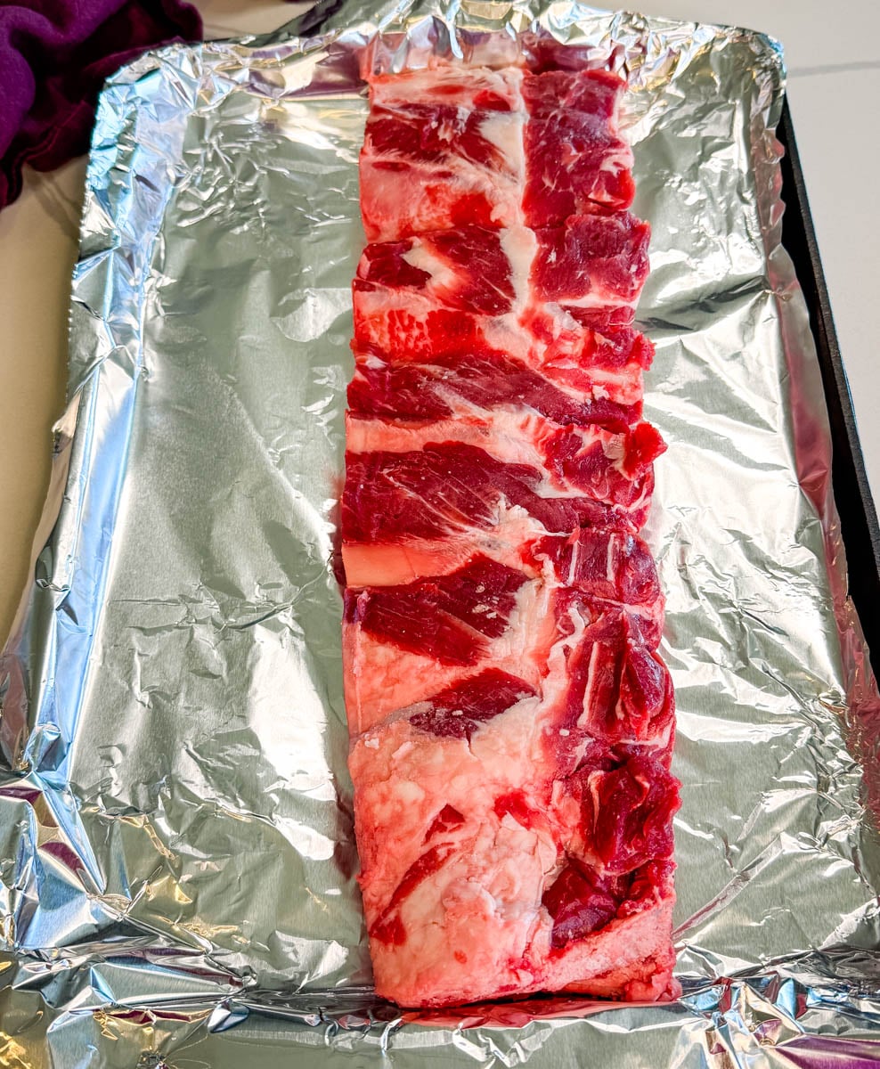 Raw beef back ribs placed on a foil-lined baking sheet ready for seasoning