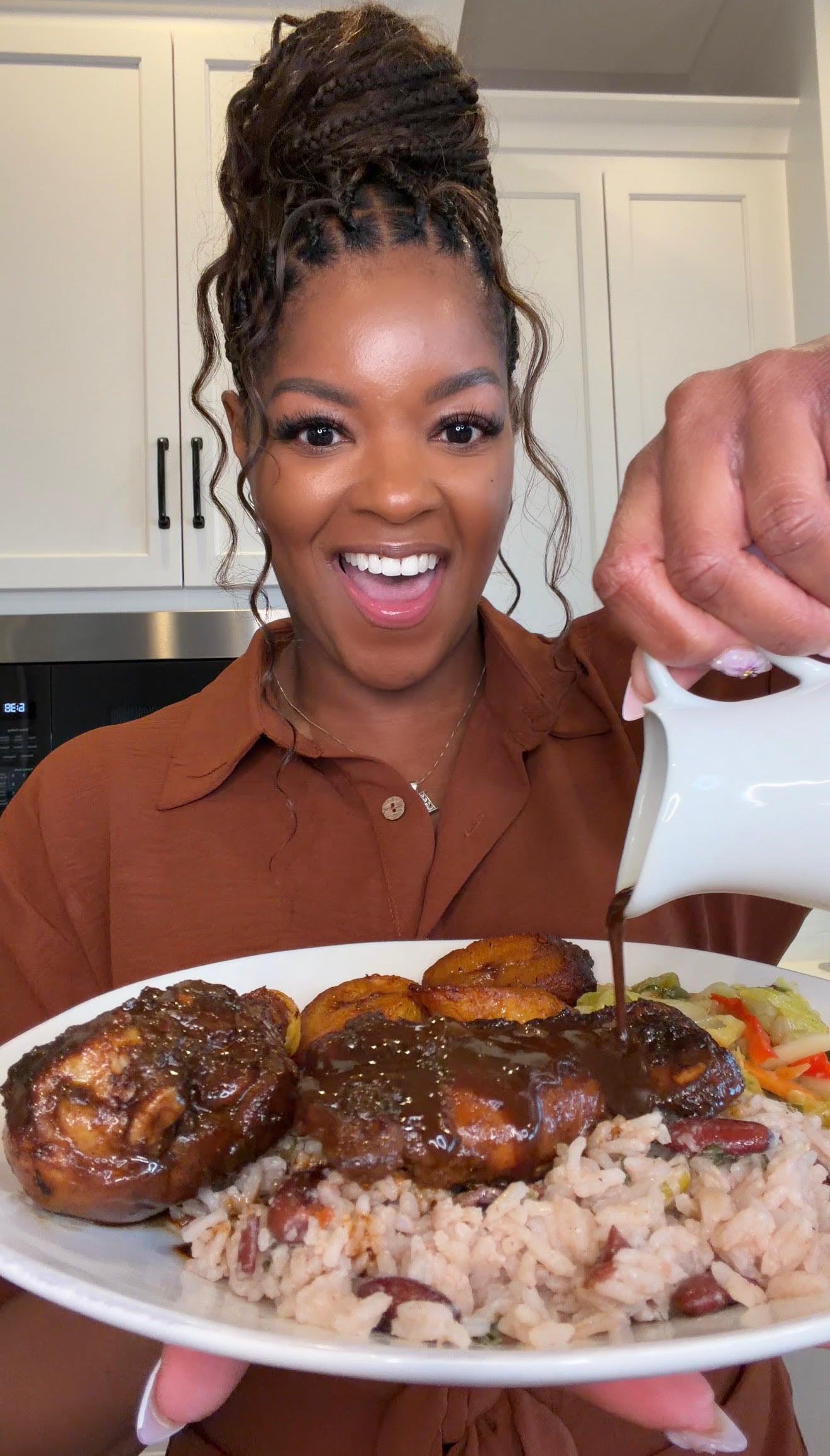 person holding a plate of brown stew chicken with rice and peas