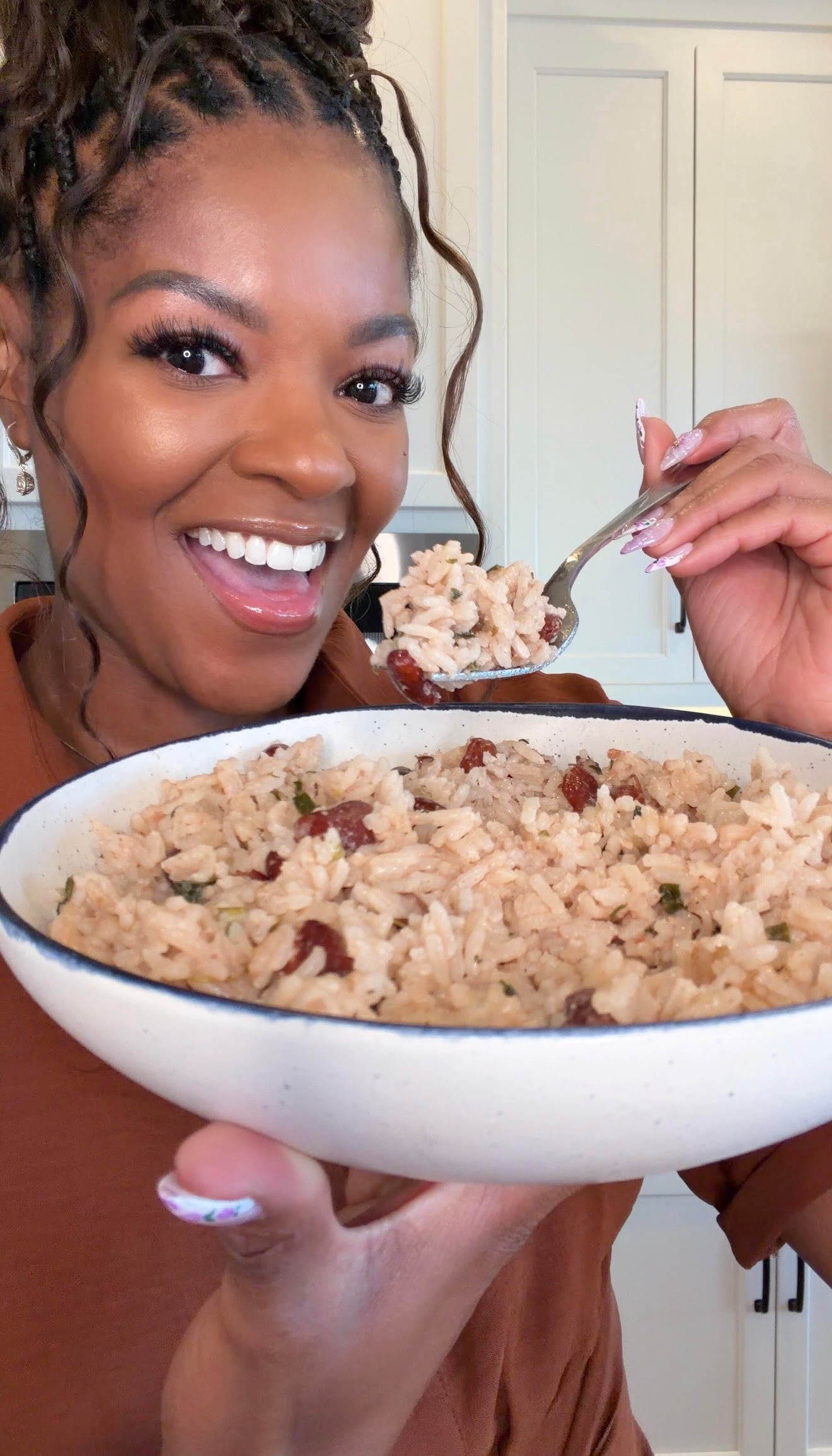 person holding a bowl of rice and peas with a fork