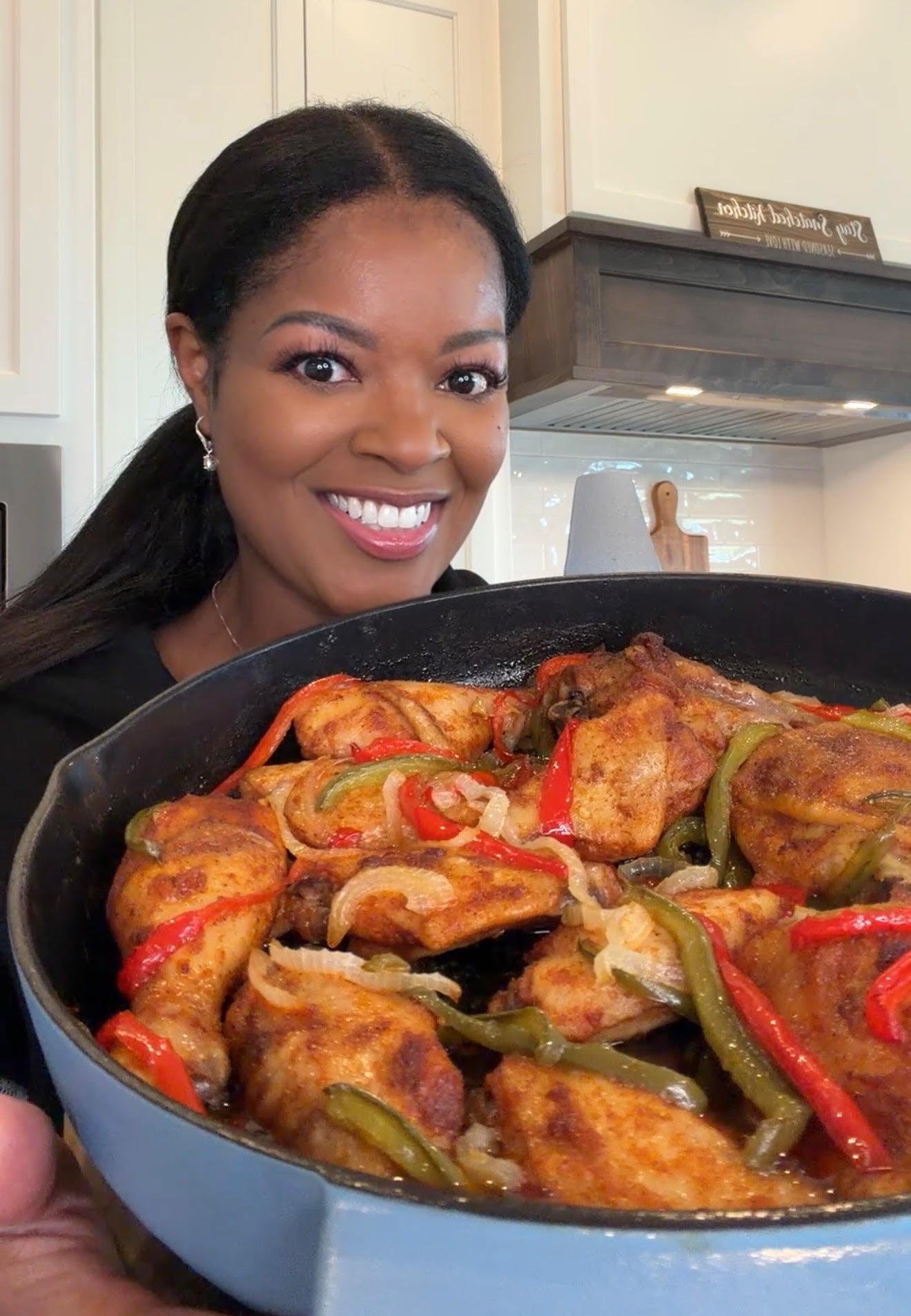 person holding a pan of baked chicken with bell peppers