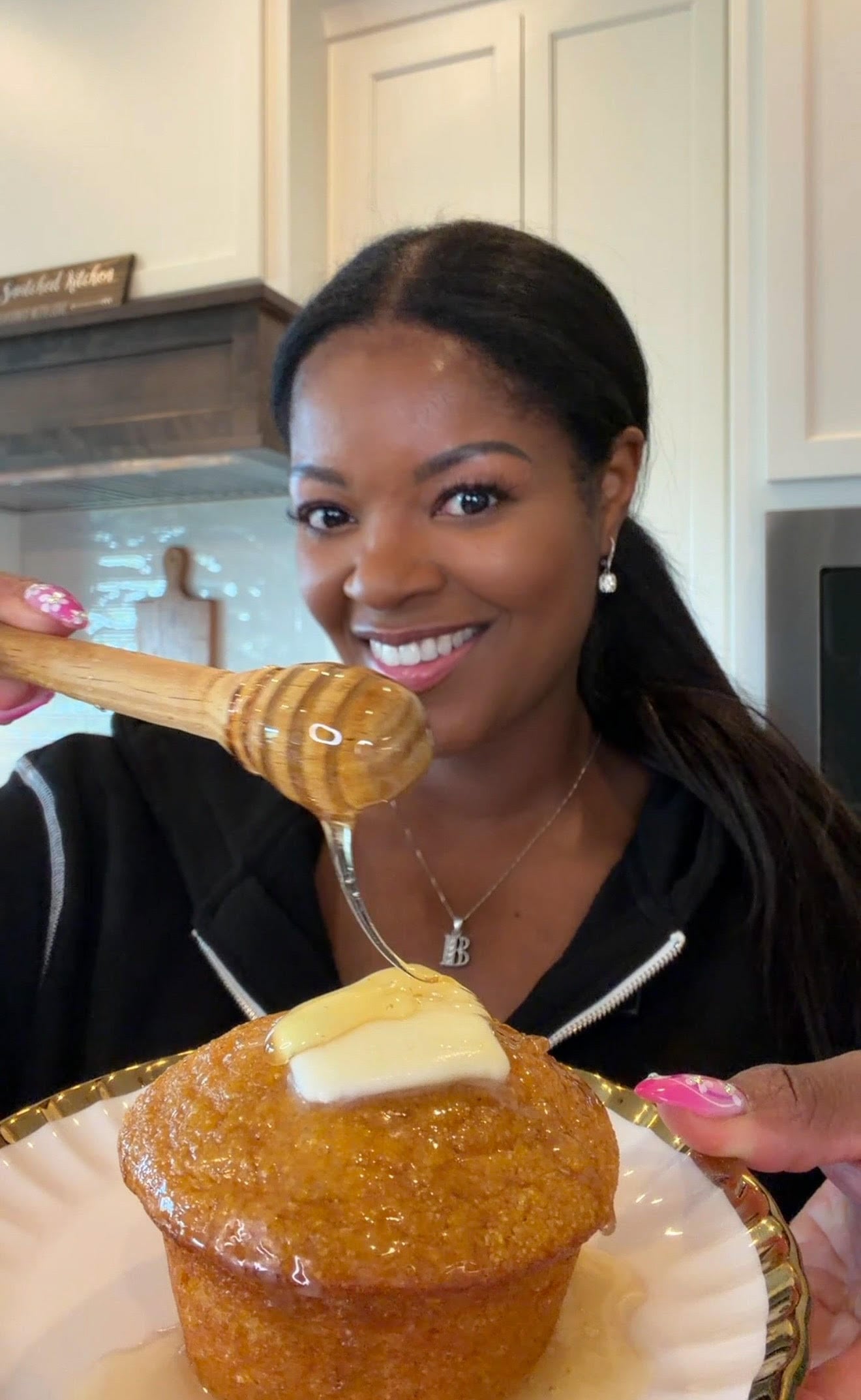 person holding sweet potato cornbread muffin and drizzling honey over it