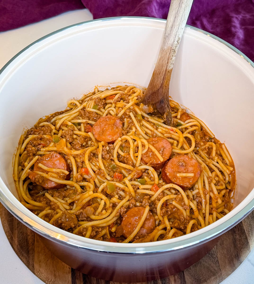 Dirty spaghetti with ground beef, smoked sausage, bell peppers, onions, and a rich tomato-based sauce in a large serving bowl.