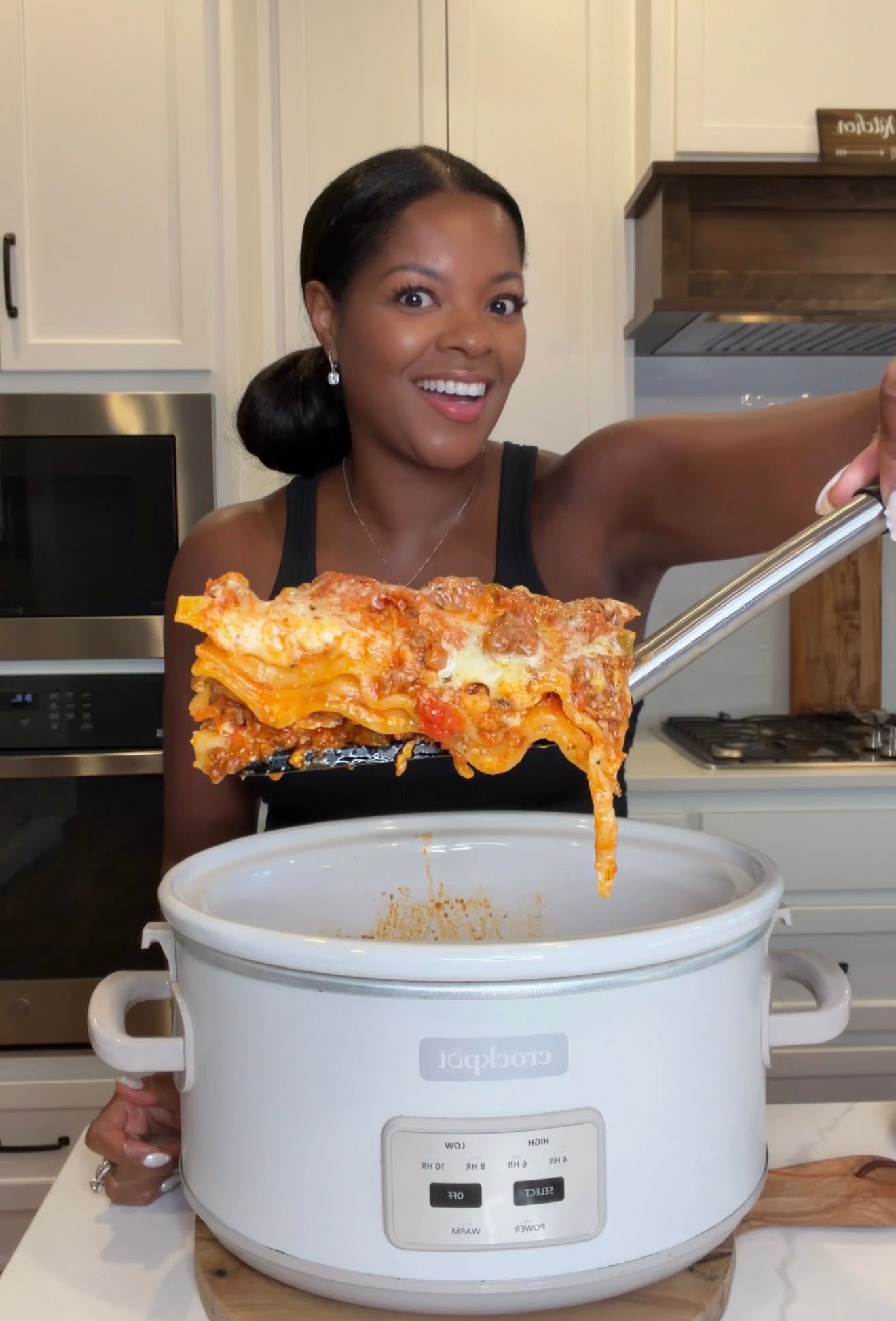 person holding a piece of lasagna over a slow cooker Crockpot