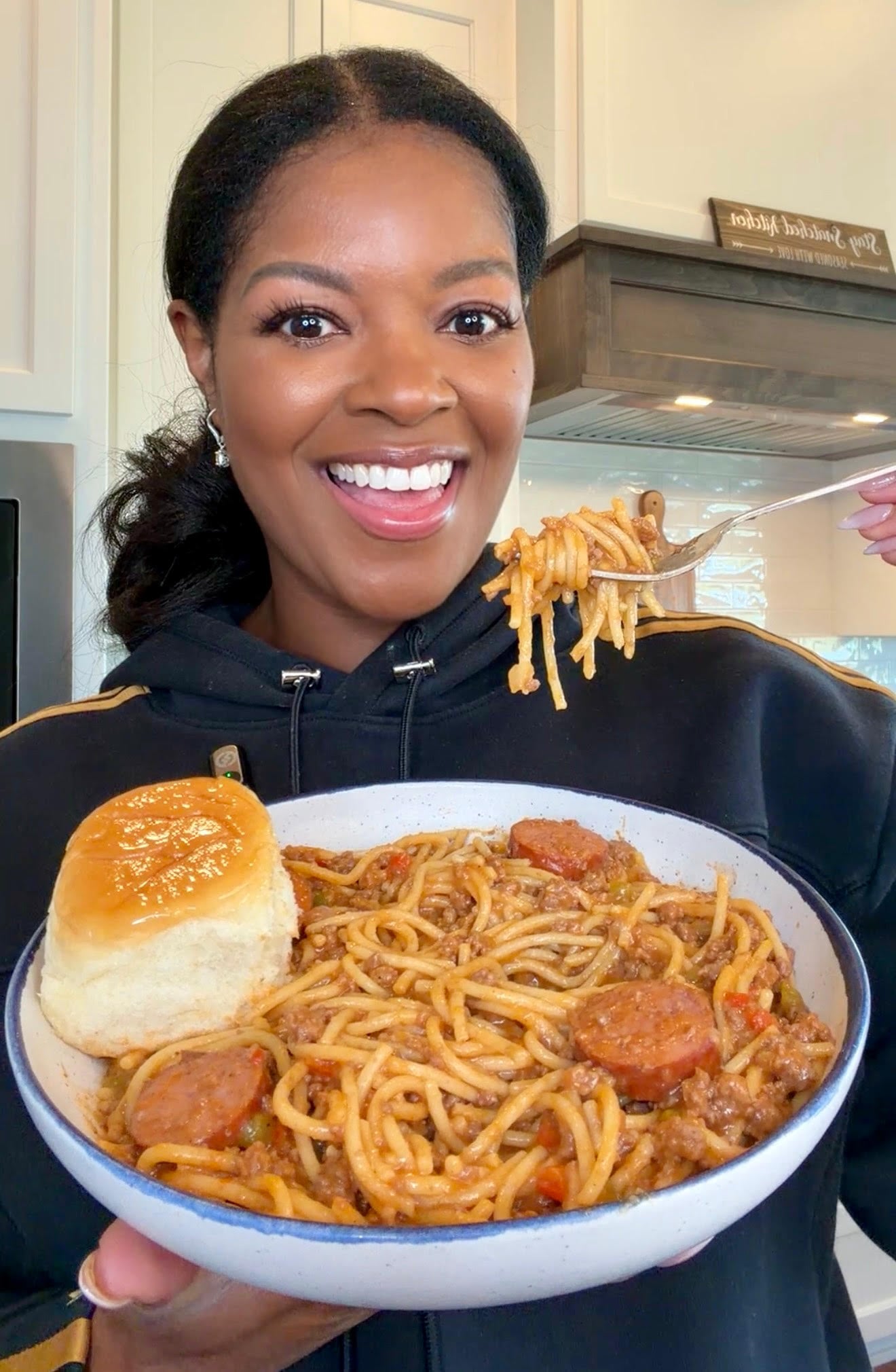 Brandi holding a bowl of dirty spaghetti with a dinner roll and fork