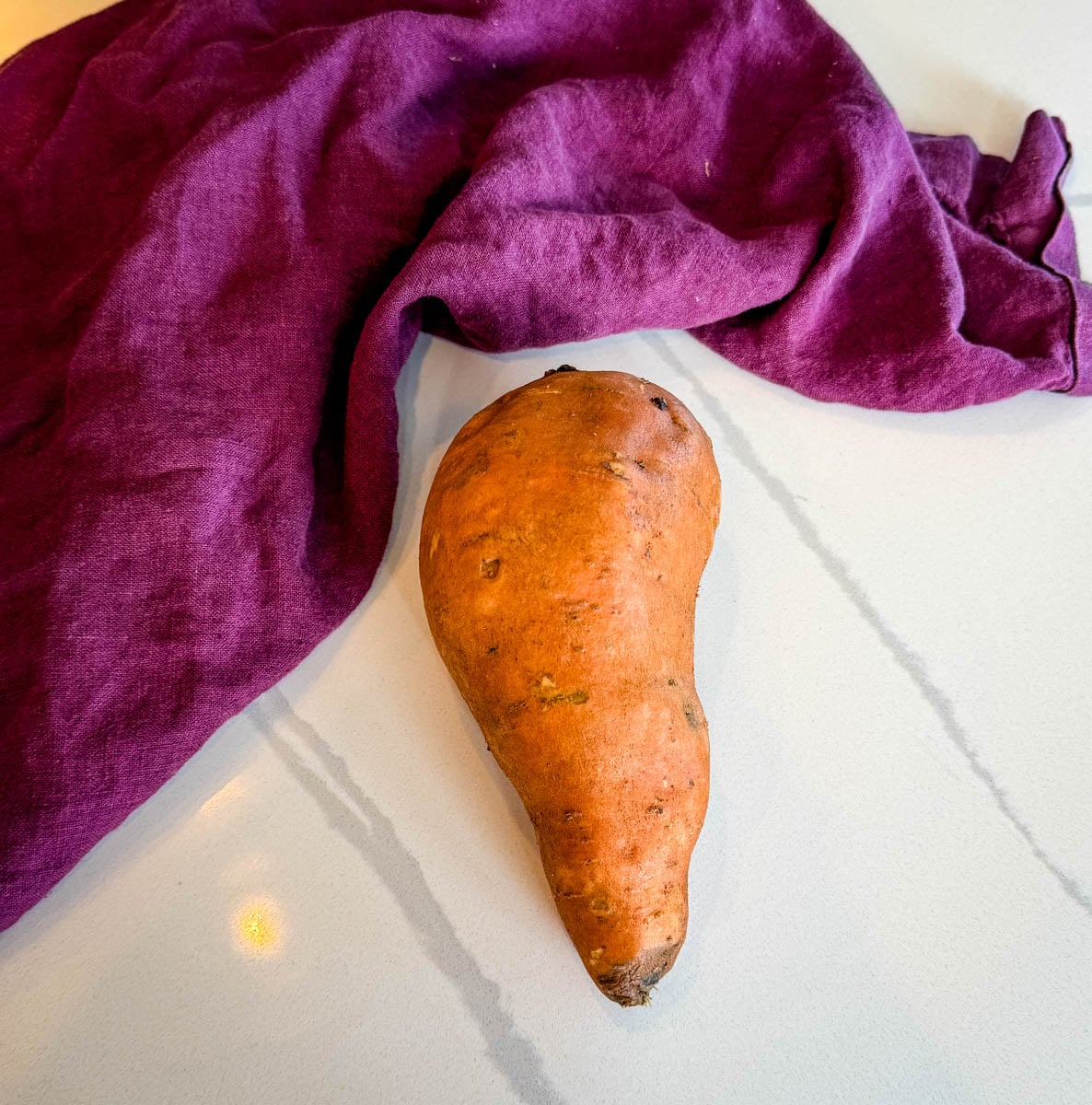 raw sweet potato on a white countertop