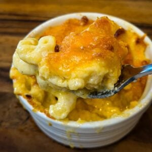 Spoonful of cheesy air fryer mac and cheese showing creamy pasta beneath a golden melted cheddar topping.