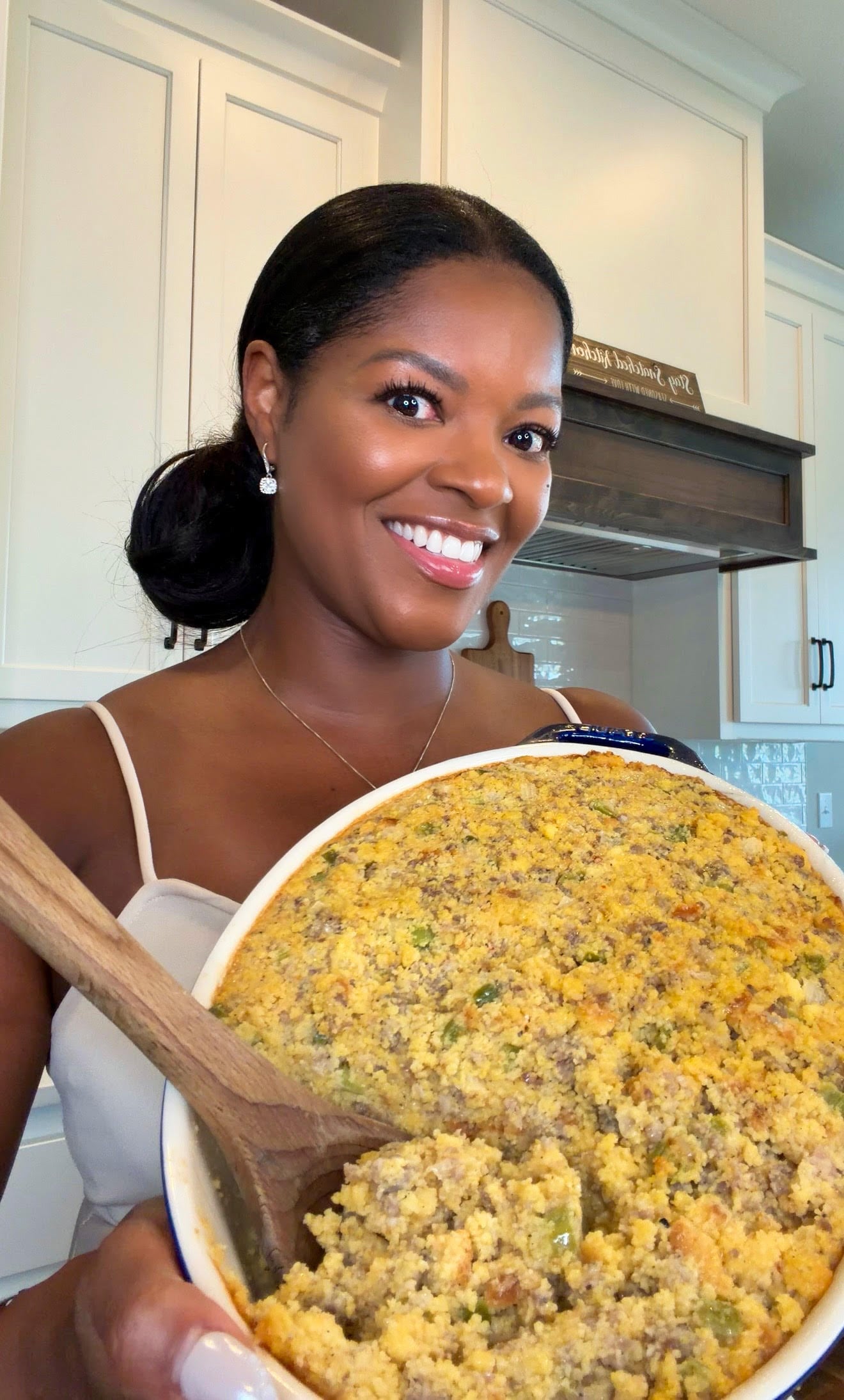 Brandi Crawford holding pan of cornbread dressing with sausage