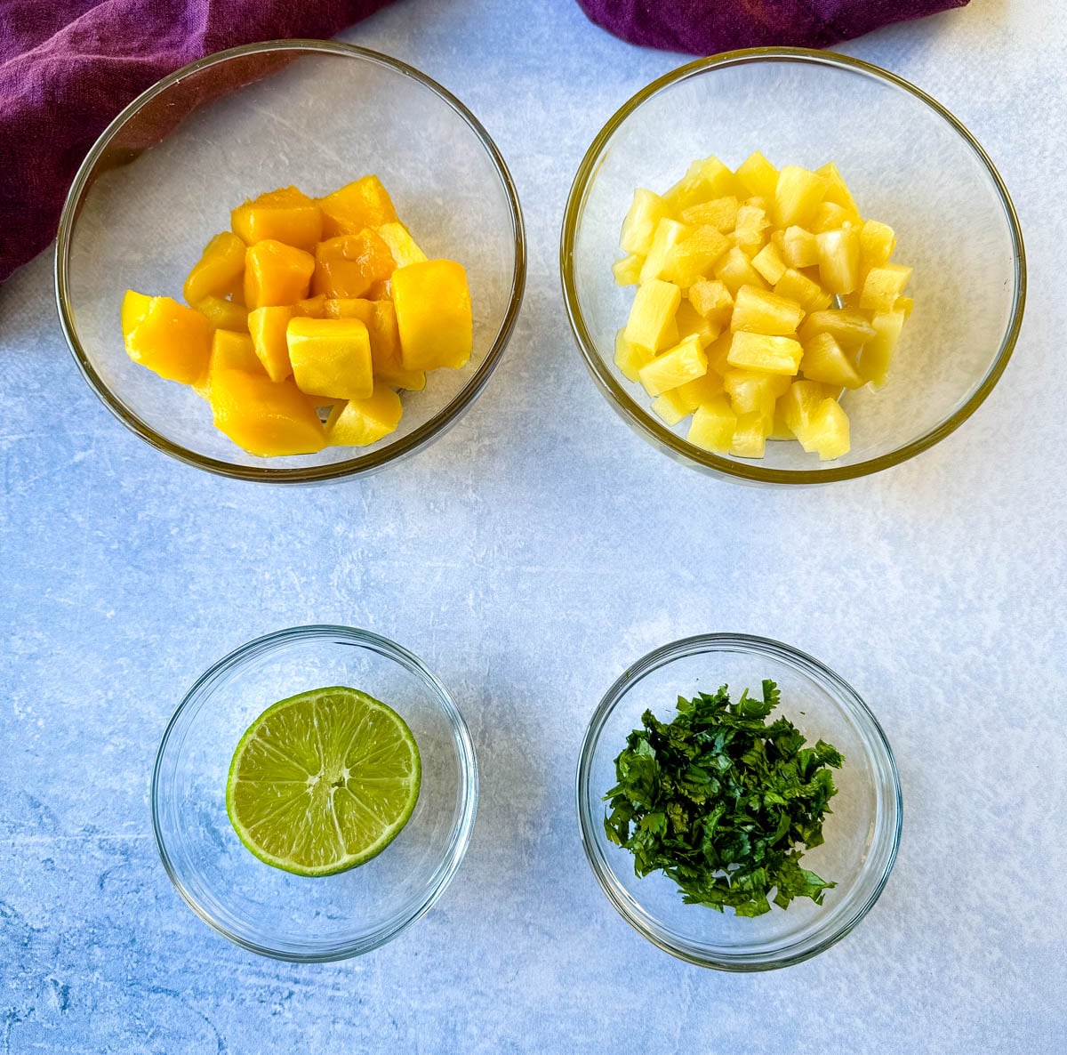 Fresh ingredients for pineapple mango salsa including chopped mango, pineapple, fresh lime, and chopped cilantro.