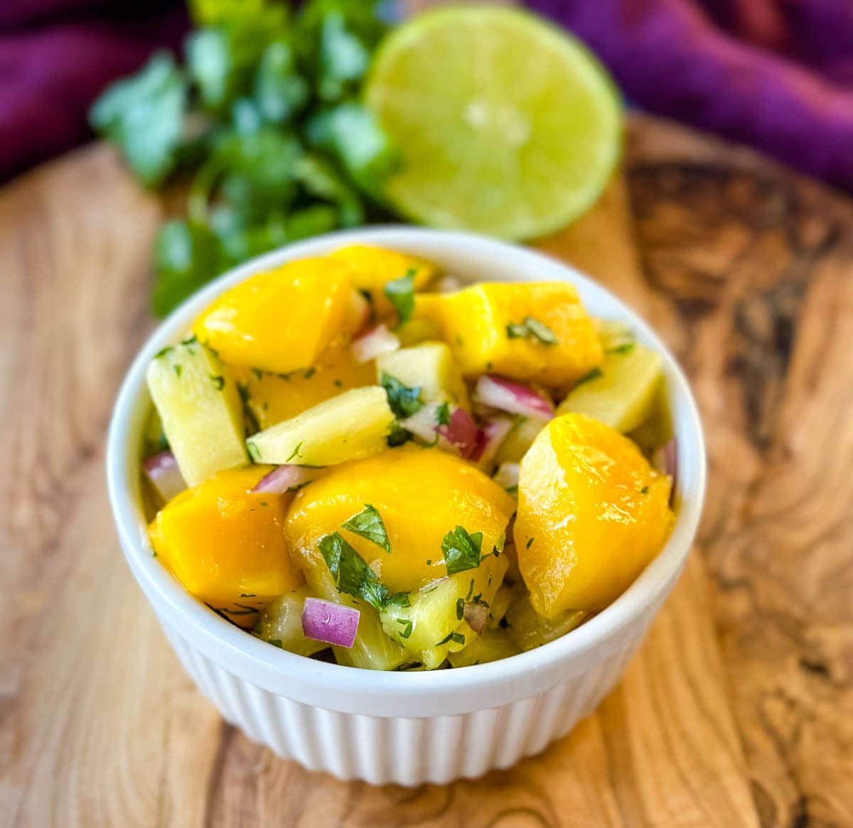 Close-up of homemade pineapple mango salsa with juicy mango, pineapple, red onion, and fresh cilantro in a white serving bowl.