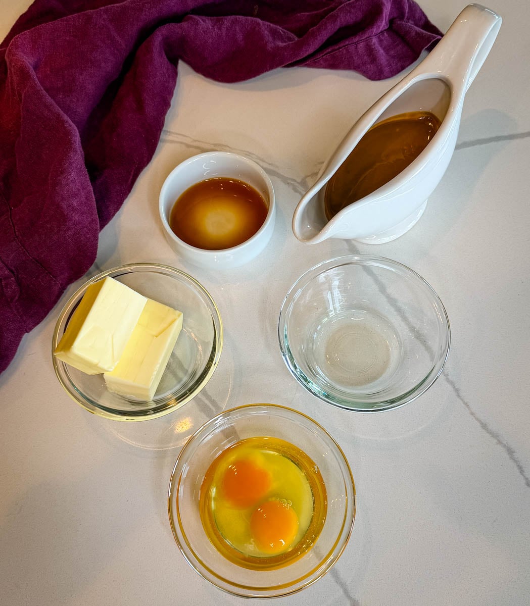 Biscoff brownie wet ingredients arranged on a countertop, including butter, oil, eggs, vanilla extract, and melted Biscoff cookie butter.