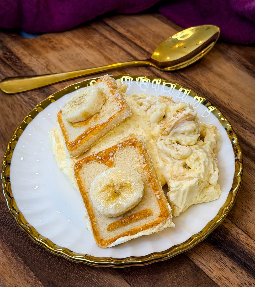 Serving of creamy Chessman banana pudding with banana slices and Chessman cookies on a white and gold plate.